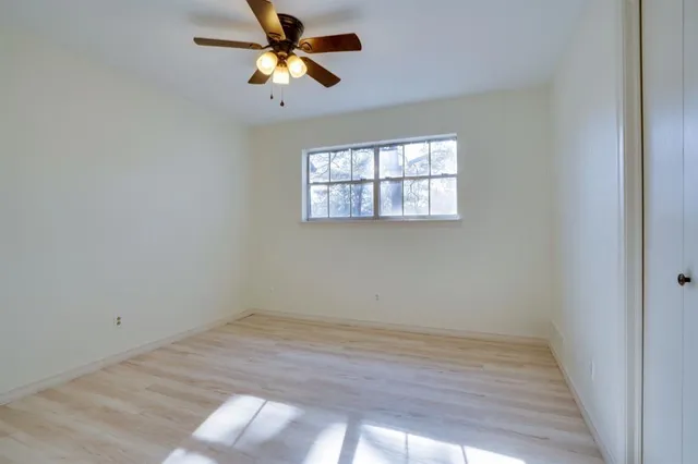 an empty room with a window and a fan