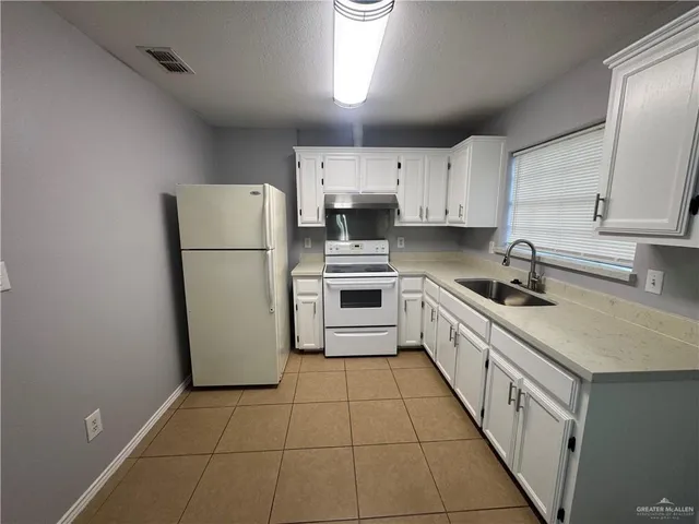 a kitchen with a sink a refrigerator and cabinets