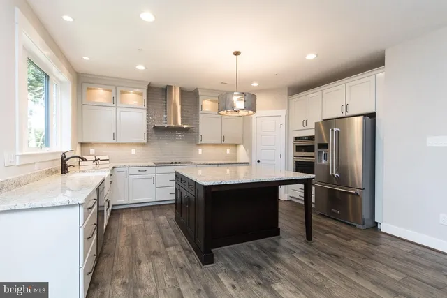 a kitchen with a center island wooden floor and stainless steel appliances