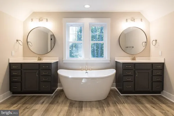 a bathroom with a bathtub a sink a mirror and a window