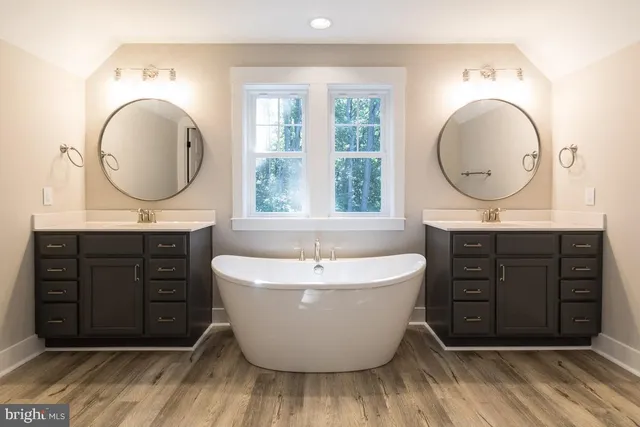 a bathroom with a bathtub a sink a mirror and a window