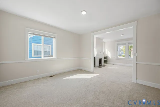 an empty room with windows and fireplace