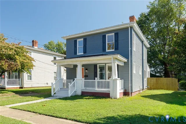 a view of a house with a yard and a large tree
