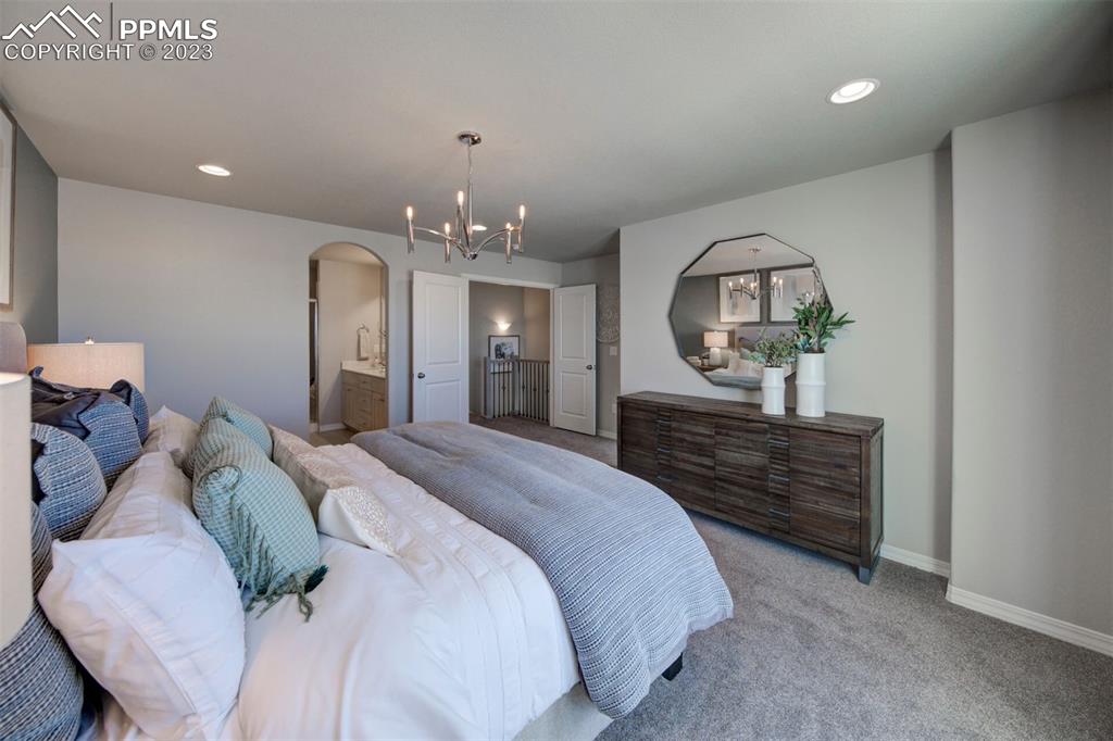 6069 Inman View Colorado Springs, CO 80924 - Photo 10 of 13 a spacious bedroom with a bed and chandelier