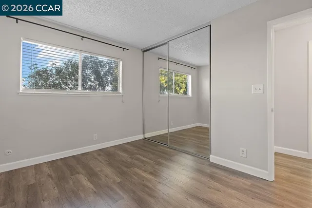 an empty room with wooden floor and windows