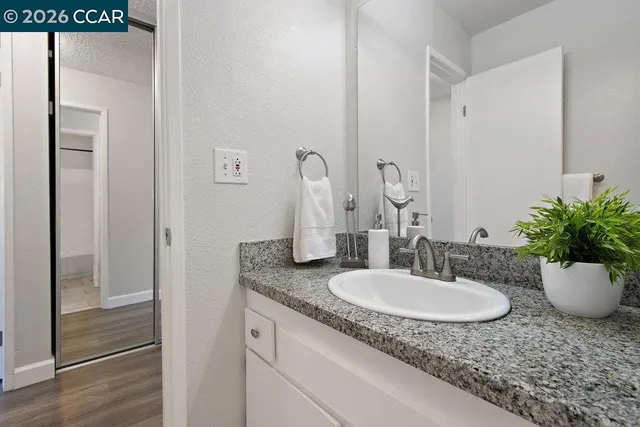 a bathroom with a granite countertop sink and a mirror