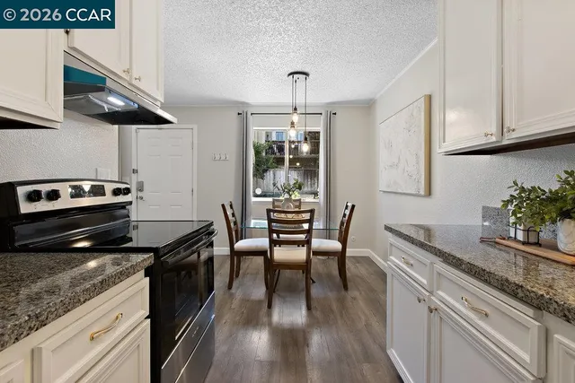 a kitchen with granite countertop stainless steel appliances a stove a sink a dining table and chairs with wooden floor