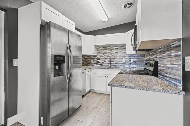 a kitchen with stainless steel appliances granite countertop a refrigerator and a sink