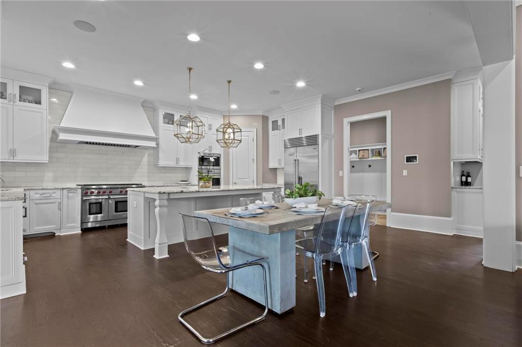 490 Belada Boulevard Atlanta, GA 30342 - Photo 11 of 42 a kitchen with stainless steel appliances kitchen island granite countertop a stove a sink a dining table and chairs