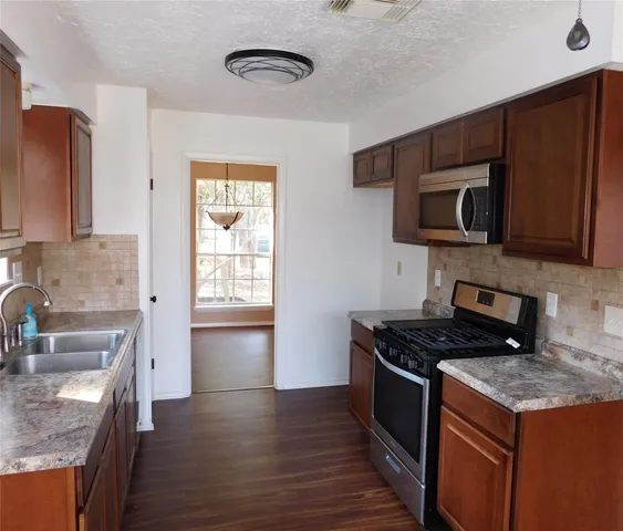 a kitchen with stainless steel appliances granite countertop a stove a sink and a microwave
