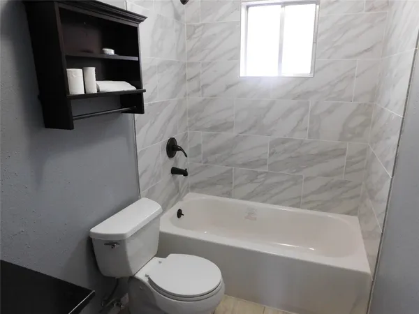 a white toilet and tub sitting next to a window