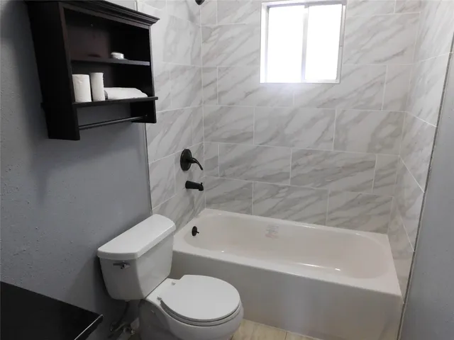 a white toilet and tub sitting next to a window