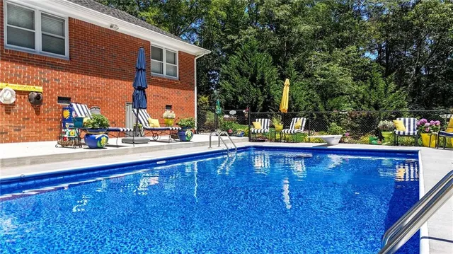 swimming pool view with two chairs and a table of chairs