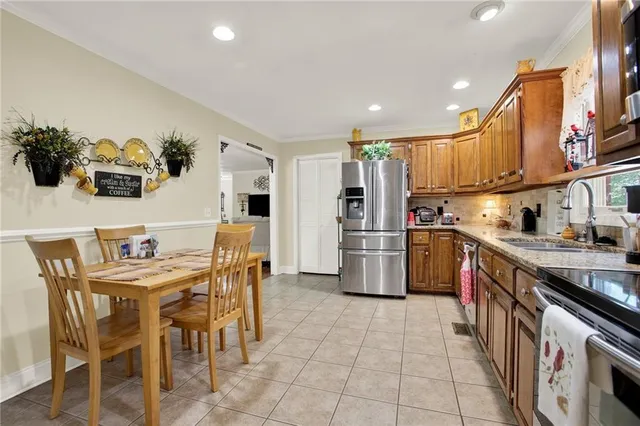 a kitchen with stainless steel appliances a refrigerator a stove a sink dishwasher with a dining table and chairs