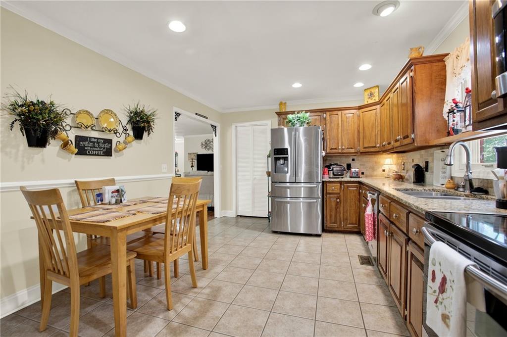 103 Mims Drive Calhoun, GA 30701 - Photo 9 of 34 a kitchen with stainless steel appliances a refrigerator a stove a sink dishwasher with a dining table and chairs