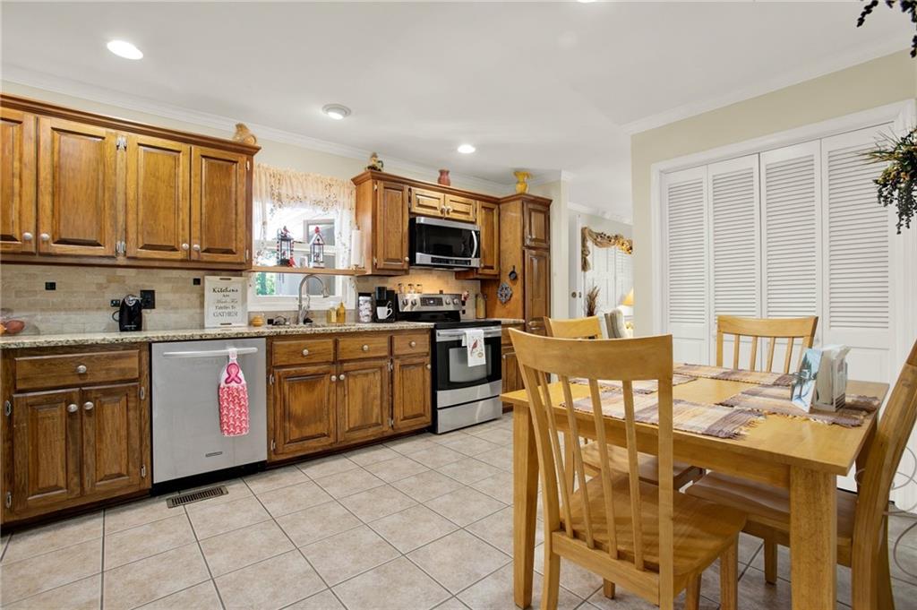 103 Mims Drive Calhoun, GA 30701 - Photo 10 of 34 a kitchen with stainless steel appliances granite countertop a stove top oven a sink a dining table and chairs