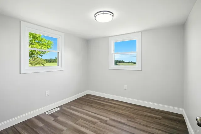 an empty room with a window and wooden floor
