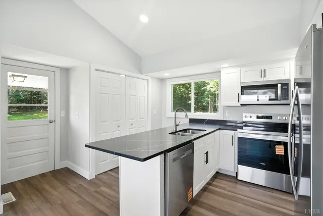 a kitchen with stainless steel appliances granite countertop a stove a sink and white cabinets