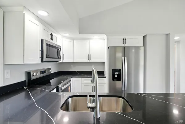 a kitchen with stainless steel appliances granite countertop a refrigerator a stove and a sink with wooden floor