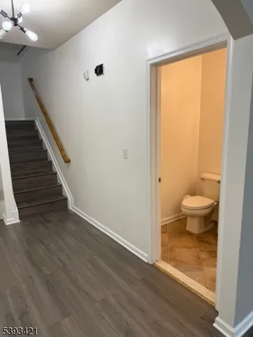 a view of a hallway with wooden floor and a toilet