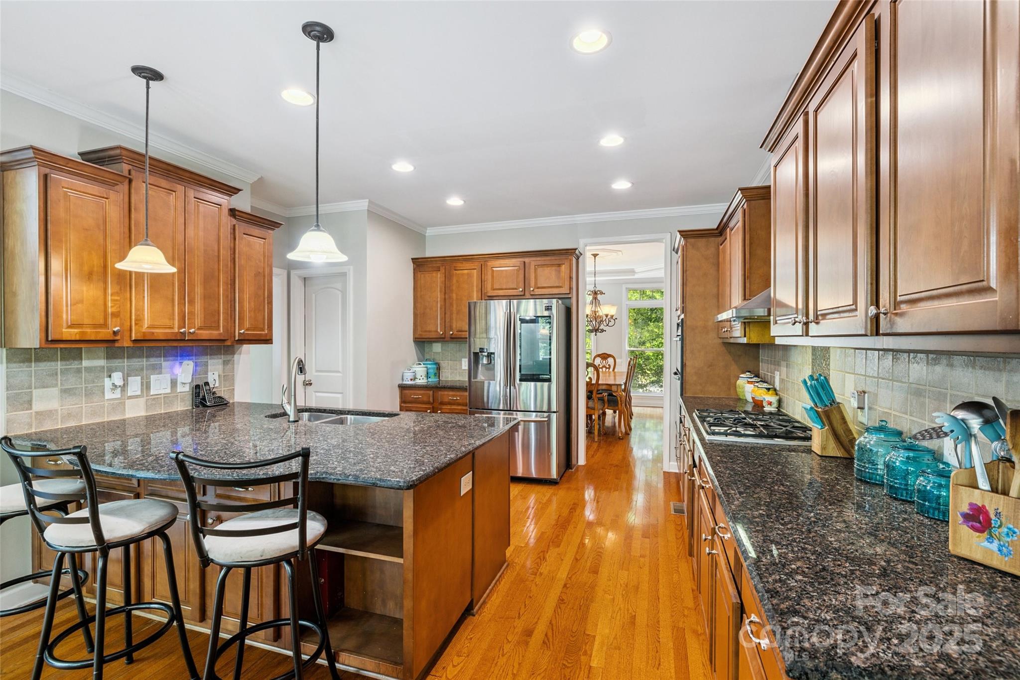 9142 Drayton Lane Indian Land, SC 29707 - Photo 18 of 48 a kitchen with granite countertop a stove a sink a dining table and chairs with wooden floor