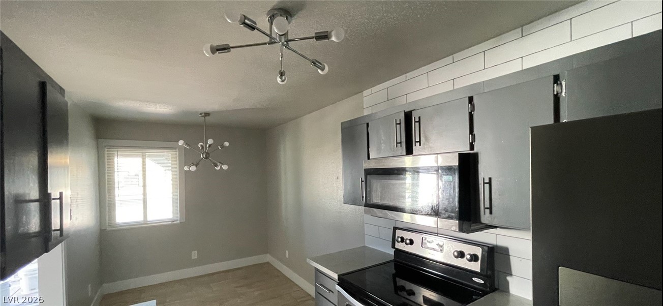 466 East Sunset Road, Unit D Henderson, NV 89011 - Photo 17 of 20 Kitchen with suspended lighting, gray cabinets, stainless steel appliances, a textured ceiling, and light countertops