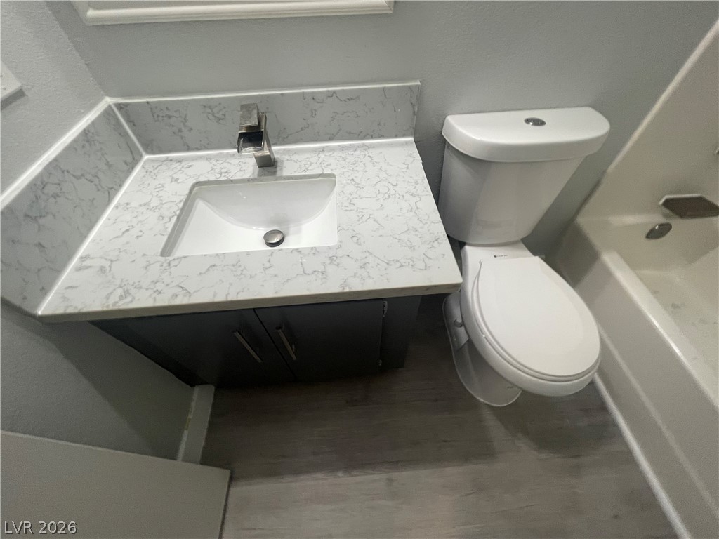 466 East Sunset Road, Unit D Henderson, NV 89011 - Photo 19 of 20 Full bathroom with vanity, a textured wall, shower / washtub combination, and wood finished floors