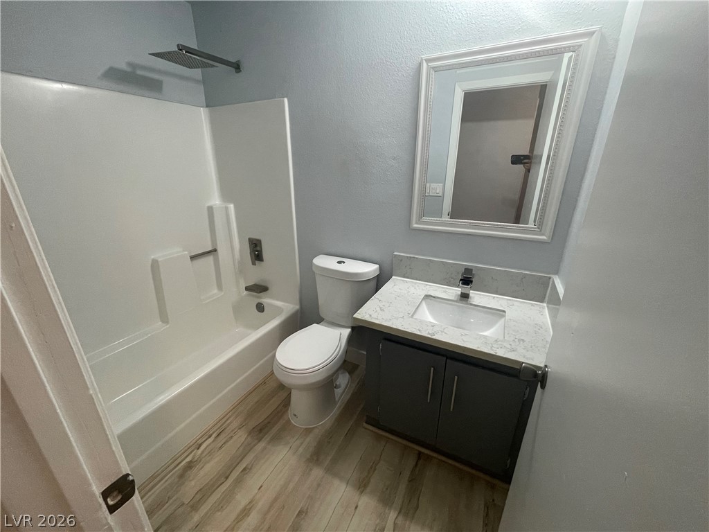 466 East Sunset Road, Unit D Henderson, NV 89011 - Photo 9 of 20 Full bathroom featuring vanity, light wood-style flooring, washtub / shower combination, and a textured wall
