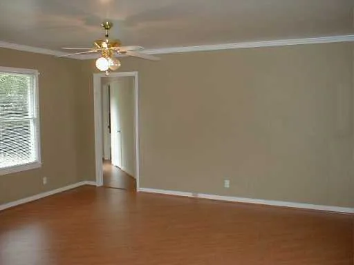 an empty room with a chandelier fan and windows