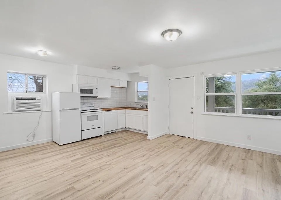 1302 South Quinlan Park Road Austin, TX 78732 - Photo 12 of 40 Kitchen with white appliances, cooling unit, light wood finished floors, white cabinets, and backsplash