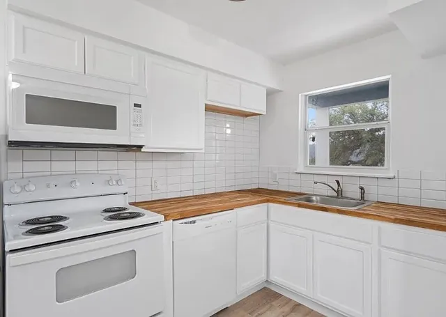 a kitchen with granite countertop white cabinets and stainless steel appliances