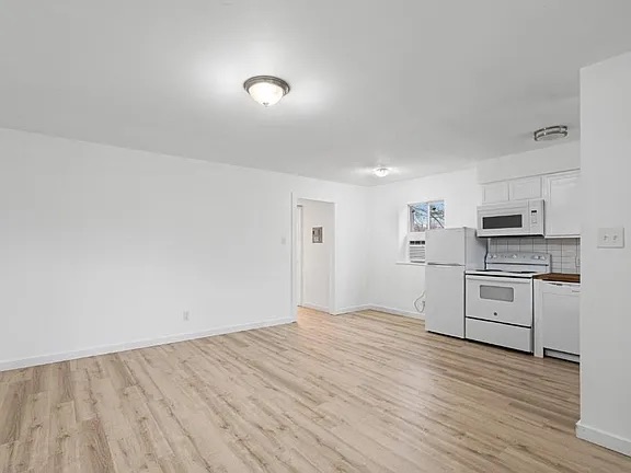 1302 South Quinlan Park Road Austin, TX 78732 - Photo 15 of 40 Kitchen featuring white appliances, light wood-style floors, white cabinetry, and tasteful backsplash