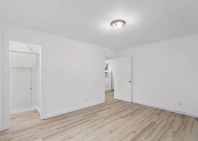 a view of an empty room with window and wooden floor