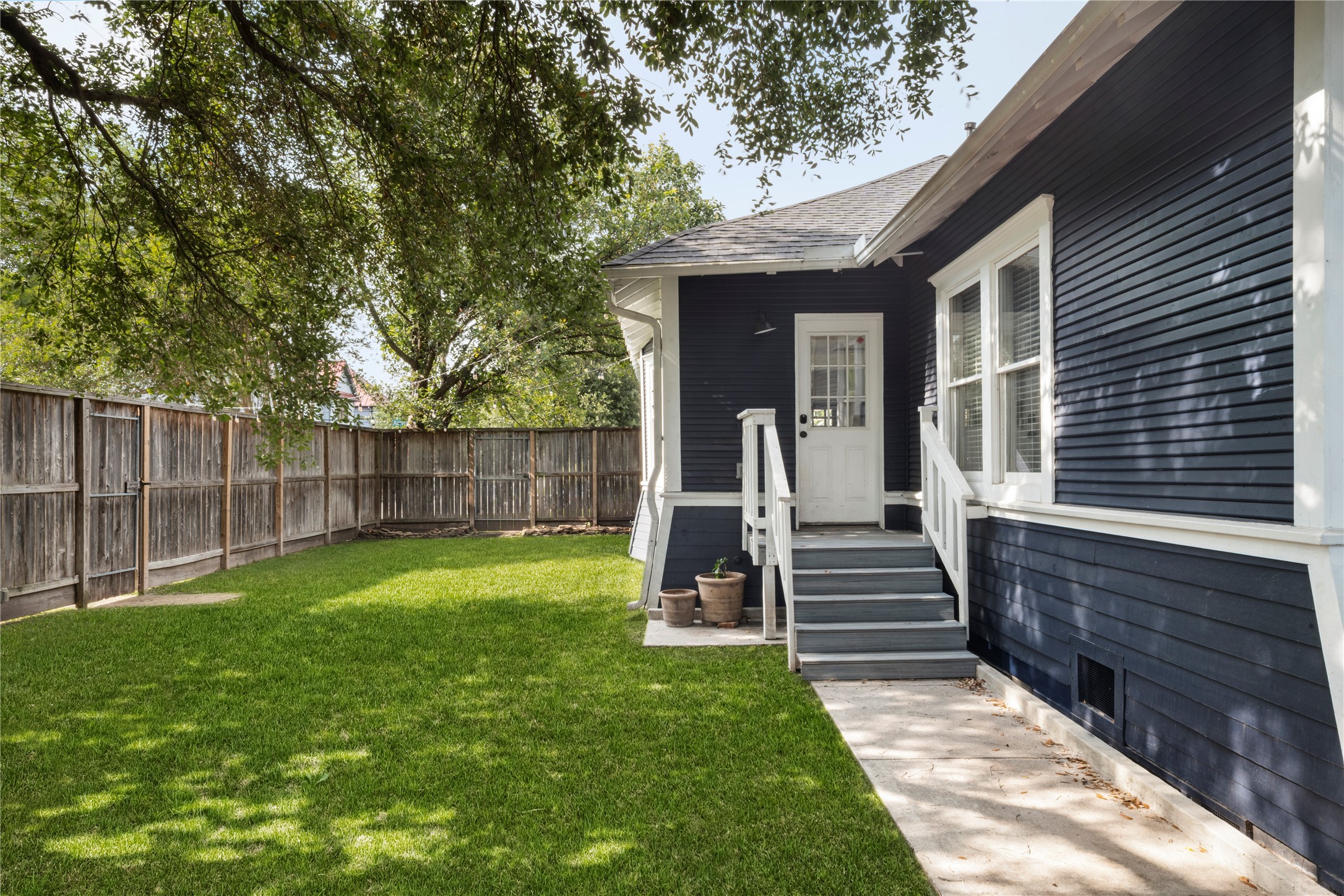602 Aurora Street Houston, TX 77008 - Photo 23 of 36 Rear exterior showing the connection between the home and outdoor space. A defined path leads to the backyard, framed by mature trees and fencing. The setting feels private while still maintaining usable space.