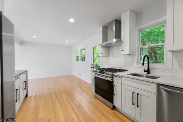 a kitchen with granite countertop a sink a stove top oven and cabinetry