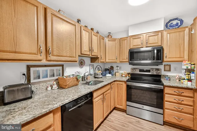 a kitchen with stainless steel appliances granite countertop a sink and cabinets with wooden floor