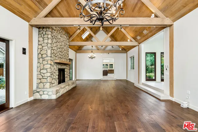 an empty room with wooden floor a fireplace and windows