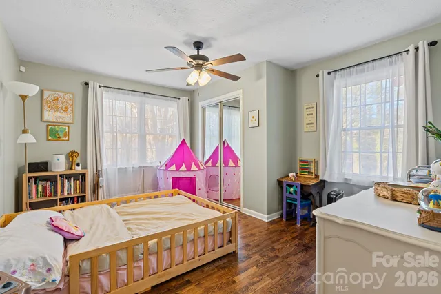 a bedroom with a bed a dresser and windows