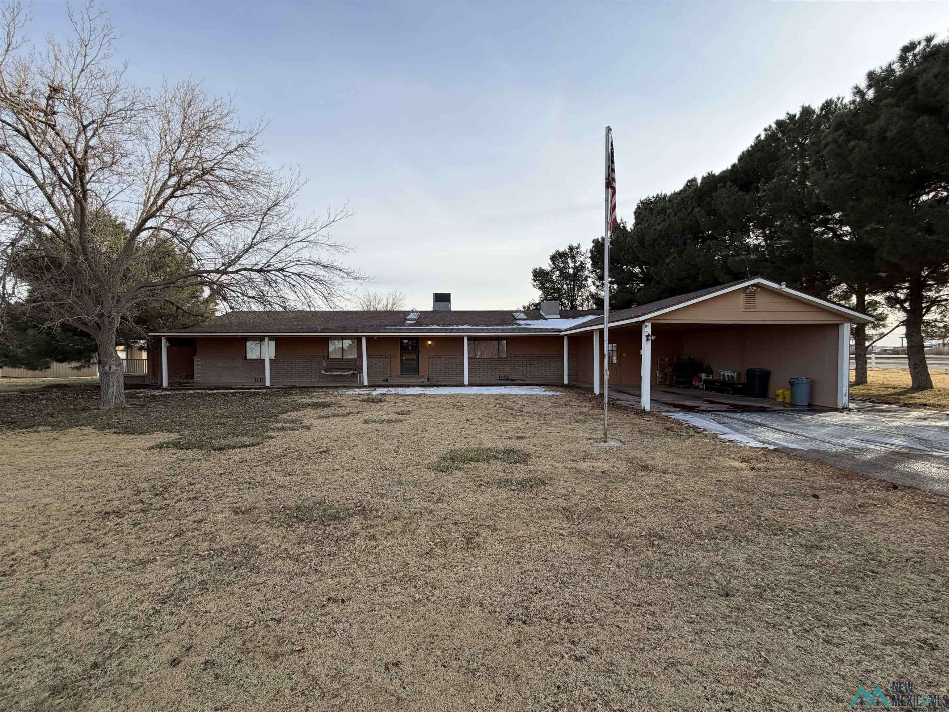 2001 East Derrick Road Carlsbad, NM 88220 - Photo 1 of 84 Ranch-style home featuring concrete driveway, a front yard, a chimney, and a carport