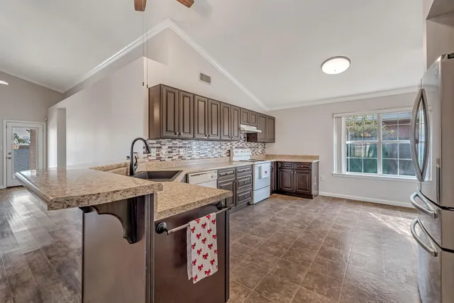 a kitchen with stainless steel appliances granite countertop a sink a stove and a refrigerator