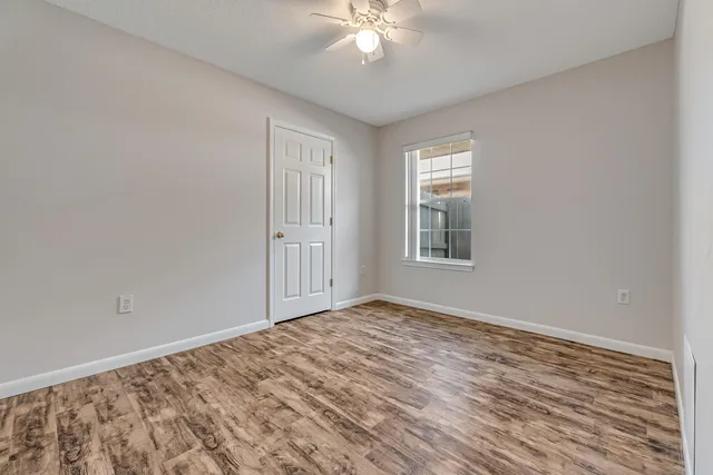 a view of an empty room with wooden floor and a window