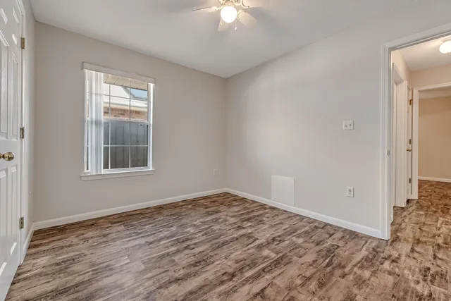 a view of an empty room with window and wooden floor