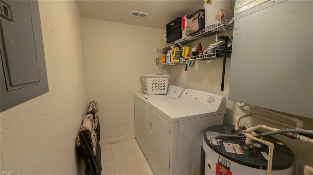 8298 Key Royal Lane, Unit 413 Naples, FL 34119 - Photo 14 of 18 Laundry room with electric panel, water heater, and washing machine and dryer