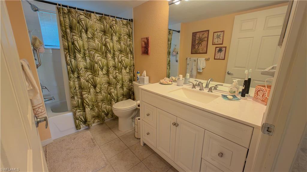 8298 Key Royal Lane, Unit 413 Naples, FL 34119 - Photo 17 of 18 Full bathroom featuring vanity, shower / tub combo with curtain, and light tile patterned flooring