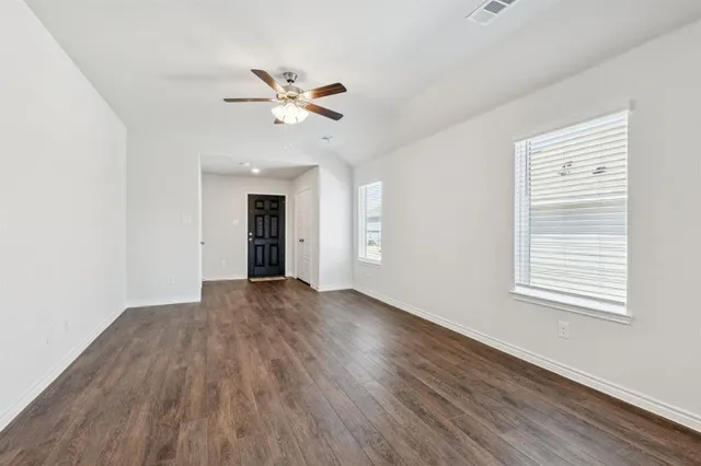 a view of empty room with wooden floor and fan