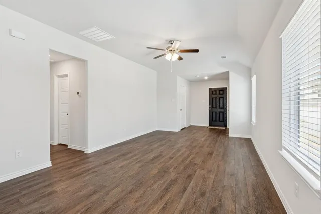 a view of empty room with wooden floor and fan