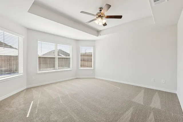 an empty room with chandelier fan and windows
