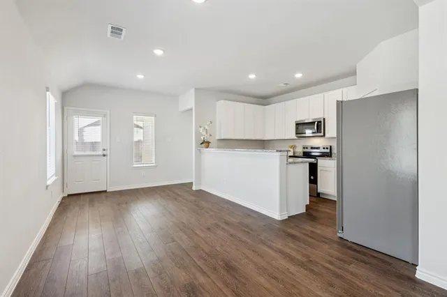 a view of kitchen with cabinets wooden floor and stainless steel appliances