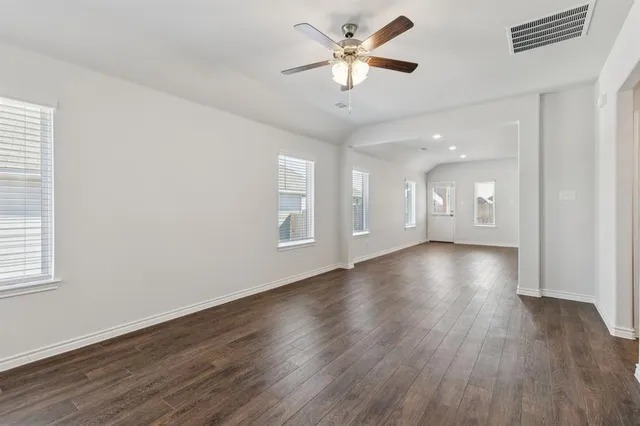a view of an empty room with a window and wooden floor