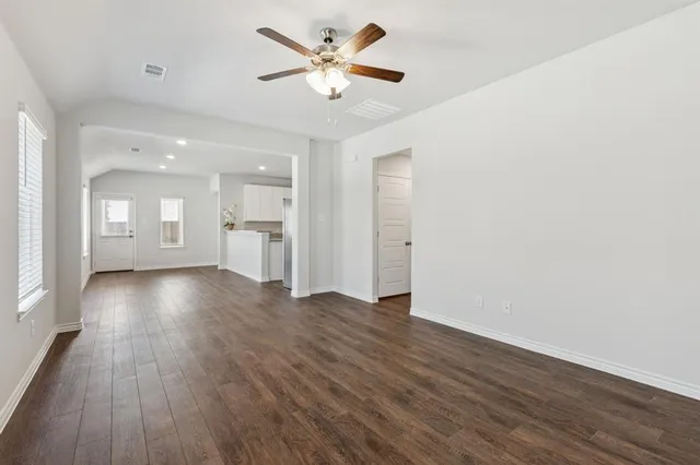 a view of an empty room with a window and wooden floor